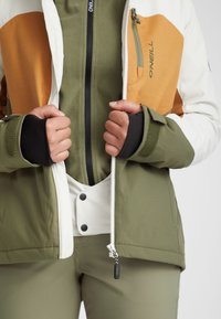 Warm, insulated jacket featuring a color-block design in white, orange, and olive green, with a zippered front and thumbhole cuffs.