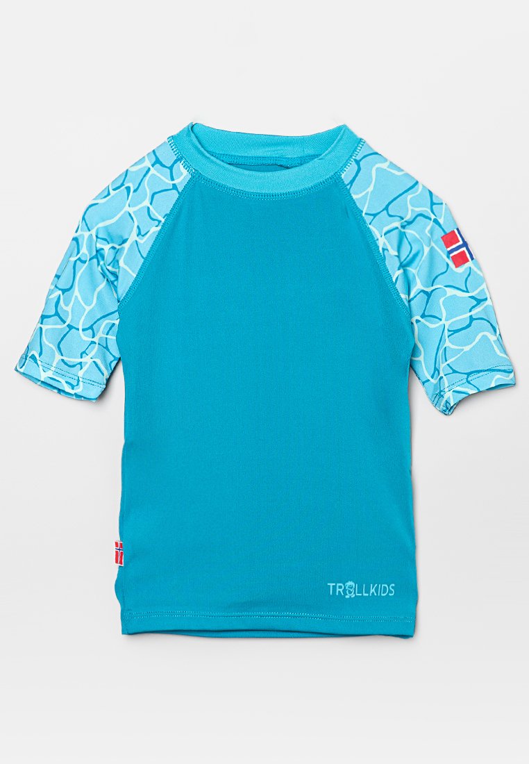 Blå kortärmad rashguard med en solid turkos kropp, mönstrade akvamarinsärmar och en liten flaggdetalj på sidan.