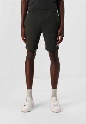 Dark green athletic shorts with an elastic waistband, side pockets, and a small logo on the hem. Fabric appears soft with a smooth texture.