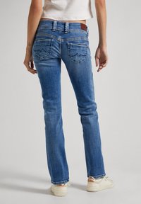 Blaue Jeans aus Denim mit einer taillierten Silhouette, ausgestattet mit hinteren Taschen mit geschwungenen Nähten und einem dezenten Lederpatch am Bund.