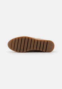 Brown rubber outsole with horizontal grooves, featuring a logo imprint. Textured surface for grip and durability. Rounded toe design.