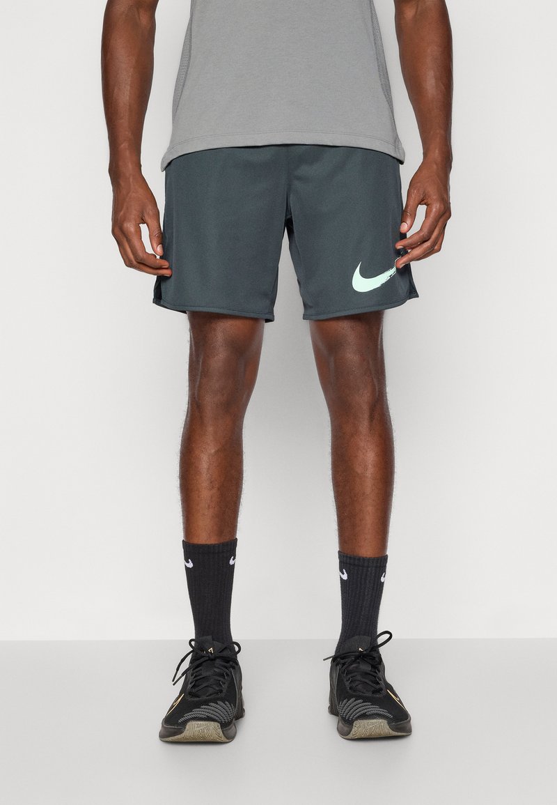 Vīriešu tumši pelēki sporta šorti ar gaiši mentolzaļu Nike logotipu. Izmantojot melnas zeķes un melnus sporta apavus, kuriem ir struktūrēts dizains un elpojošs audums.