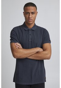 Námořnická polos tričko s krátkými rukávy, knoflíkovou légou a strukturovanou látkou. Obsahuje malou logo aplikaci blízko lemu. Standardní střih.