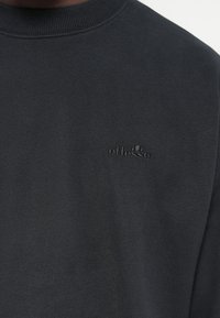 Felpa grigio scuro con colletto a girocollo a coste, morbida al tatto e con logo ricamato tono su tono sul petto.