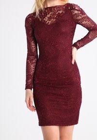 Bordeaux-Spitzenkleid mit langen Ärmeln, figurbetonter Silhouette, floralem Muster und transparenter Halslinie. Sanfte Textur mit glatter Oberfläche.