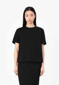T-shirt noir à manches courtes avec un col rond. Design simple, en tissu doux, coupe droite, sans motifs ni embellissements visibles.