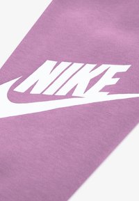 Μωβ βαμβακερό ύφασμα με υφή υφαντού, με εμφανές λευκό λογότυπο «Nike» και καμπύλο λευκό σχέδιο μουστάκι.