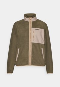 Chaqueta de forro polar verde oliva con un panel frontal beige, cierre de cremallera, cuello alto y logo negro en el bolsillo del pecho; tejido texturizado.