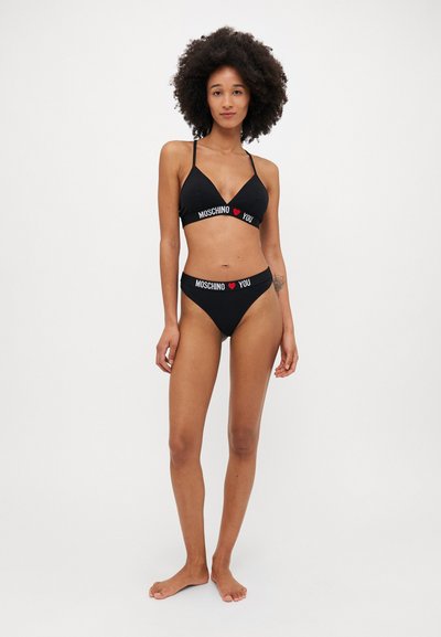 Melna bikini komplekts ar trīsstūra formu augšdaļā un augstām vidukļa biksēm. "MOSCHINO ❤️ YOU" logo izdrukāts baltā un sarkanā krāsā uz elastīgām joslām.