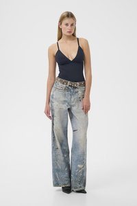 Mørkeblå badedragt med tynde stropper, kombineret med slidte lyseblå bredbenede jeans med malerpletter og slidte detaljer.