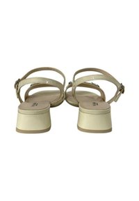 Sandali in pelle patinata beige con tacco a blocco. Presentano cinturini alla caviglia regolabili e una suola liscia, offrendo un design contemporaneo.