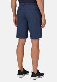 Shorts blu navy in materiale leggero, con una texture liscia, fronte piatto e due tasche posteriori. Indossati con scarpe da ginnastica nere.