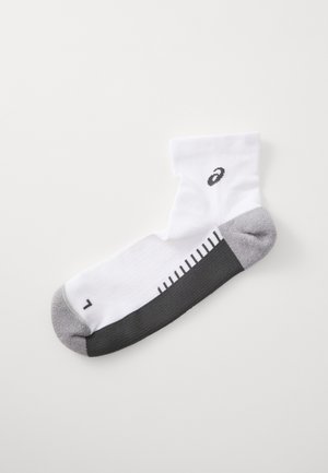 Bāli sporta zeķe ar pelēku papēdi un purngalu, ar melnu logotipu un izmēru atzīmēm pelēkajā daļā. Izgatavota no struktūrētas auduma.