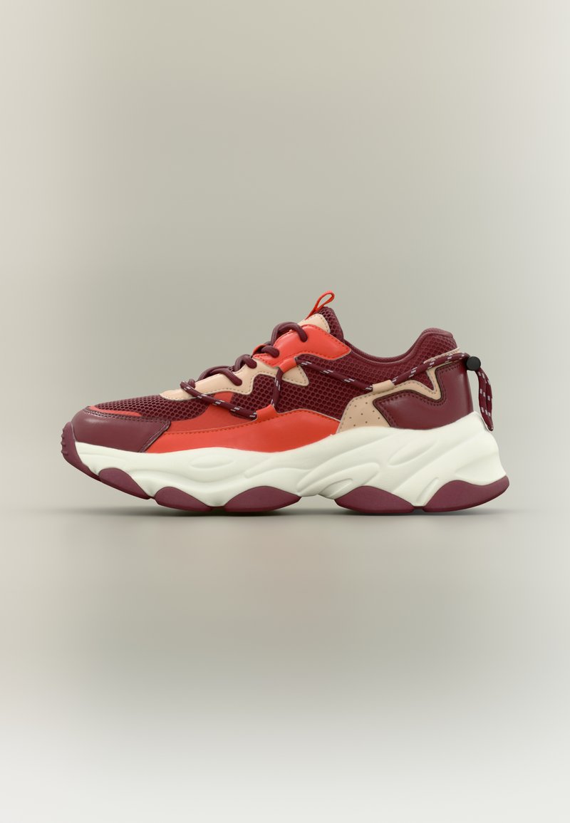 Sport sneaker with a mesh and synthetic upper in maroon, red, and cream. Bulky white midsole with pronounced grooves, contrasting rubber outsole.