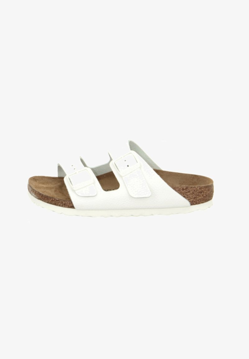 White dual-strap sandal with a textured upper, adjustable buckles, cork footbed, and a rubber outsole with a wave pattern.