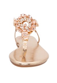 Sandali piatti dorati con un design floreale decorato con strass rosa e trasparenti, completati da una comoda suola metallica.