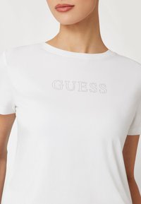 Guess MIT STRASSLOGO VORN - Marškinėliai su spaudiniu - weiß