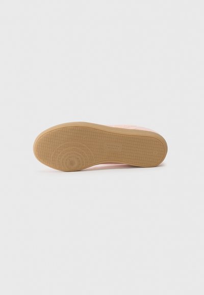 Suola di sneaker rosa con una suola in gomma testurizzata. La superficie presenta un motivo di grip ondulato e un accento circolare vicino al tallone.