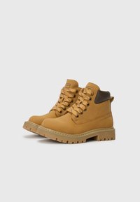 Bottes tan en cuir avec lacets et col rembourré. Semelle extérieure en caoutchouc épaisse et texturée avec un design de crantage pour une bonne adhérence.