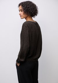 Maglione marrone con stampa leopardata, maniche lunghe e scollo rotondo. Presenta strisce laterali a contrasto e una vestibilità comoda.