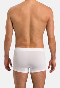 Vita bomullsboxer med elastisk midjeband, figursydd design och kort benlängd; visad från bakvyn.