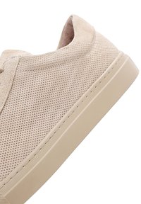 Beige Sneaker mit einem perforierten Wildleder-Obermaterial und einer leichten, beigen Gummisohle. Verfügt über minimale Nähte und ein abgerundetes Design der Zehenpartie.