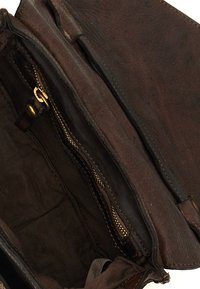 Interno di una borsa in pelle marrone con una tasca con zip e un rivestimento in tessuto testurizzato. Presenta accessori in ottone e dettagli di cucitura visibili.
