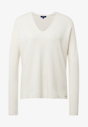 Kremowy sweter z długim rękawem i dekoltem w serek, wykonany z teksturowanej tkaniny, o prostym kroju i z małą naszywką z logo na dole.