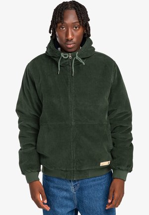 Green corduroy jacket with a hood, front zipper, drawstring, and two lower pockets. Ribbed cuffs and hem, textured fabric.