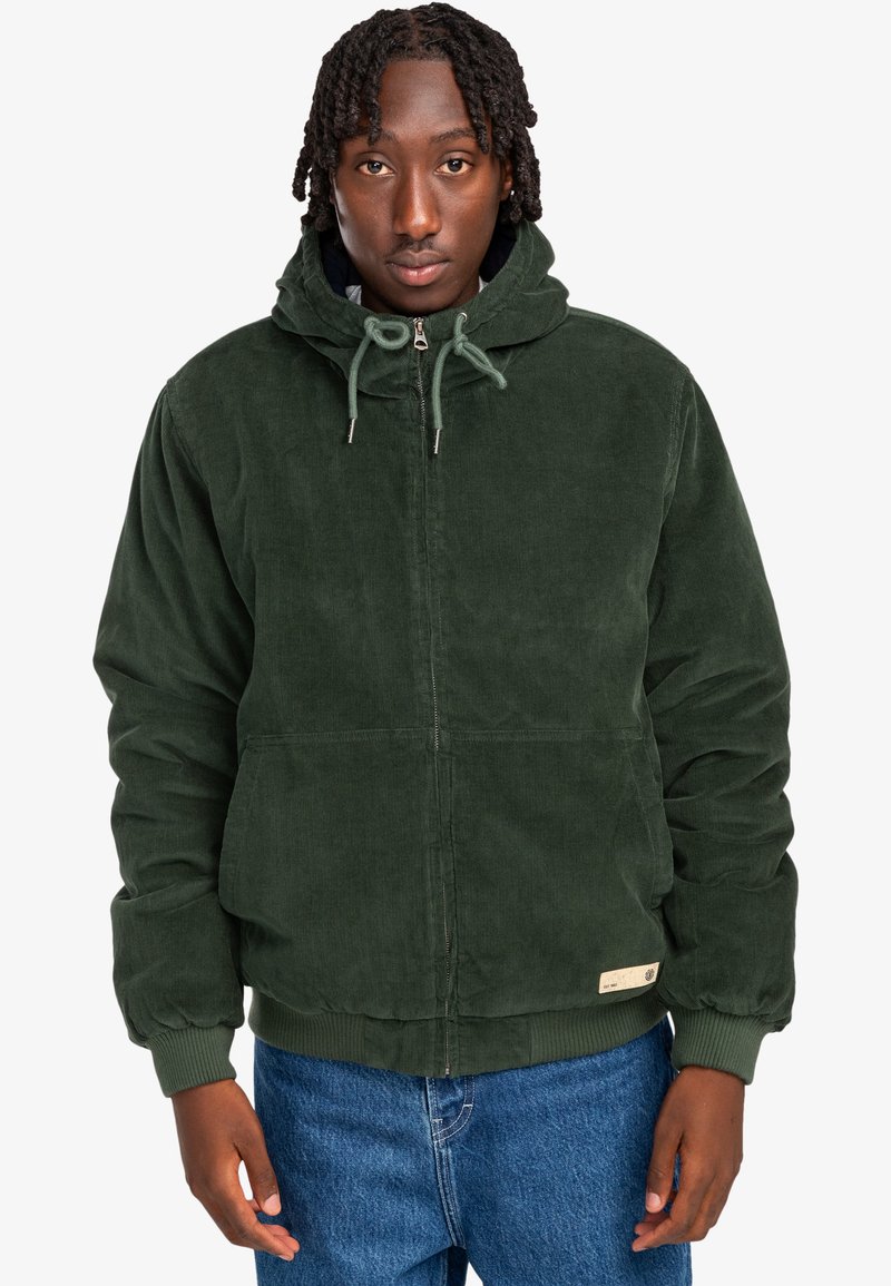Grüne Cordjacke mit Kapuze, Reißverschluss an der Vorderseite, Kordelzug und zwei unteren Taschen. Gerippte Bündchen und Saum, strukturierter Stoff.