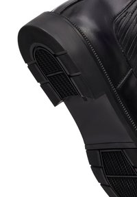 Stivale in pelle nera con tomaia liscia, motivi testurizzati sui lati e suola in gomma resistente con un design di battistrada aderente.