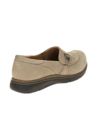 Beige suede slip-on shoe with a rounded toe, stitching details, and an adjustable strap with a decorative button. Rubber outsole for grip.