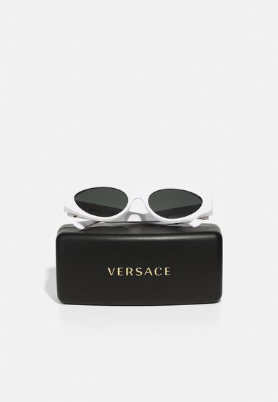 Weiße Cateye-Sonnenbrille mit dunklen Gläsern, die auf einem schwarzen rechteckigen Etui mit goldener "VERSACE"-Beschriftung liegen.