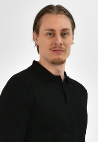 Zwarte polo met een klassieke kraag, voorzien van een twee-knopen-knopsluiting en een gladde, effen textuur. Model heeft lichtbruin haar.