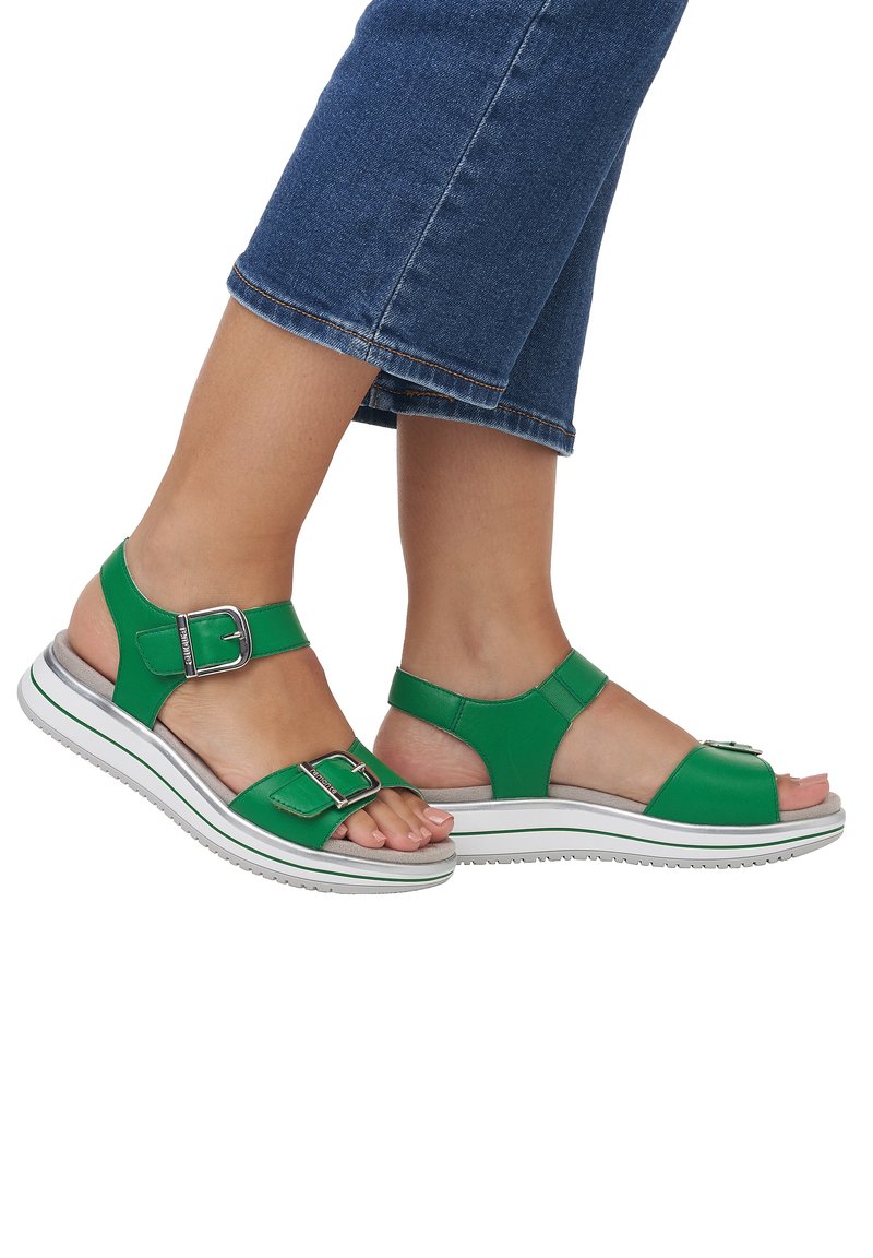 Grüne Ledersandalen mit verstellbaren Schnallen, offenes Zehen-Design und einer gepolsterten weißen Sohle mit dezenten grünen Akzenten.