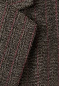 Tessuto in tweed a spina di pesce in tonalità marrone e nero con sottili righe rosse, che presenta una finitura texturizzata e un motivo classico.