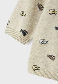 Ljusbeige tröja med ribbad ärm, med ett upprepat mönster av små broderade fordon i svart, brunt och gult.