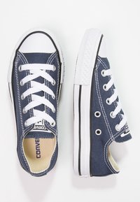 Baskets en toile bleu marine avec lacets blancs, embout en caoutchouc et semelle texturée. Comprend des œillets en métal et un logo sur la languette.