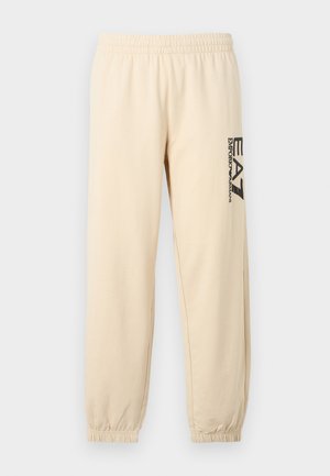 Vaaleat beiget collegehousut, joissa on joustava vyötärö, kapenevat lahkeet ja musta sivulogo, valmistettu pehmeästä ja kevyestä kankaasta.