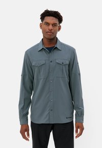 Camicia a maniche lunghe di colore verde tenue, con due tasche frontali, chiusura con bottoni e un tessuto morbido e leggero. Logo del marchio sull'orlo.