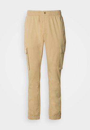 Beige cargo bukser med elastisk talje, frontknap og sidelommer. Lavet af blød, holdbar stof med en ensfarvet tekstur.