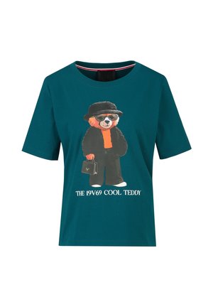 Petrolkleurig shirt met korte mouwen met een afbeelding van een teddybeer die een zonnebril draagt, een zwarte hoed, een zwarte outfit, een tas vasthoudt, en de tekst "THE 19V69 COOL TEDDY".