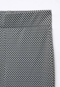 Svart och vit mönstrad tyg med ett fiskbensmönster. Har en platt, slät midja och en texturerad yta.