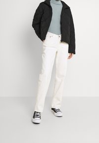 Sort quilted jakke, lyseblå ribbet sweater, hvide straight-leg jeans og sorte canvas sneakers med hvide såler.