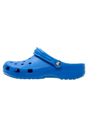 Blauer Gummiclog mit Belüftungslöchern und verstellbarem Riemen mit einem runden schwarz-weißen Logo.