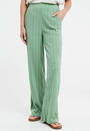 Pantaloni a gamba larga di un verde chiaro, con sottili righe verticali, caratterizzati da una vita alta e tasche laterali. Realizzati in un tessuto testurizzato.