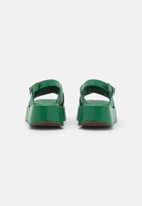 Zelené platformové sandály s otevřenou zadní částí, nastavitelním popruhem a texturovanou stélkou. Hladký povrch s masivním podpatkem.