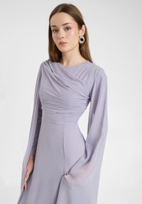 Lavendelkleurige jurk met een gedrapeerde bodice en lange, vloeiende mouwen. Gemaakt van gladde stof met een strakke taille voor een slanke uitstraling.