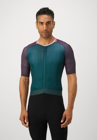 Maillot de cyclisme pour homme en turquoise et violet, à manches courtes avec une fermeture éclair à l'avant. Tissu texturé, design ajusté, avec une ceinture contrastante.