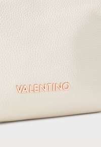 Fehér textúrájú bőrtáska, rózsa arany színű, dombornyomott "Valentino" logóval az alján.